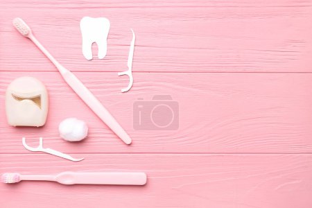 Foto de Composición con hilo dental, mondadientes y cepillos sobre fondo de madera rosa - Imagen libre de derechos
