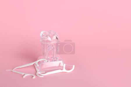 Foto de Mondadientes de hilo dental y modelo de diente de plástico sobre fondo rosa - Imagen libre de derechos