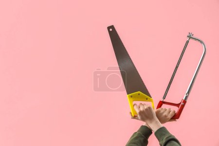 Téléchargez les photos : Mains féminines tenant différentes scies sur fond rose - en image libre de droit