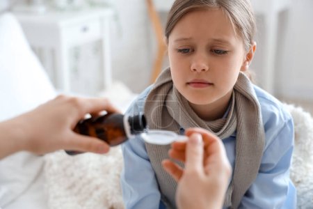 Photo for Ill little girl taking cough syrup in bedroom, closeup - Royalty Free Image