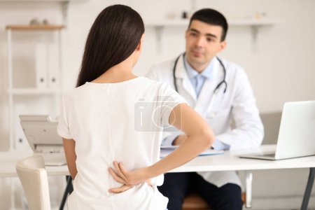 Photo for Young woman with bad posture visiting doctor in clinic, back view - Royalty Free Image