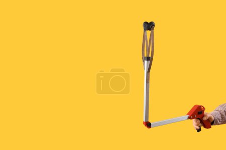 Photo for Female hand holding long reach grabber tool on yellow background - Royalty Free Image