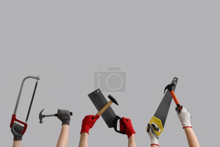 Téléchargez les photos : Mains féminines et masculines dans des gants tenant différents outils de construction sur fond gris - en image libre de droit