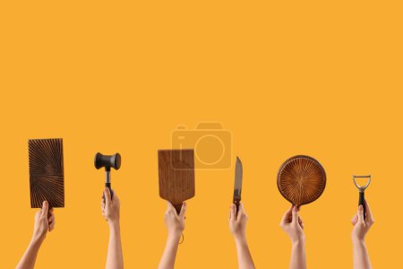 Photo for Female hands holding cutting board and different kitchen utensils on yellow background - Royalty Free Image