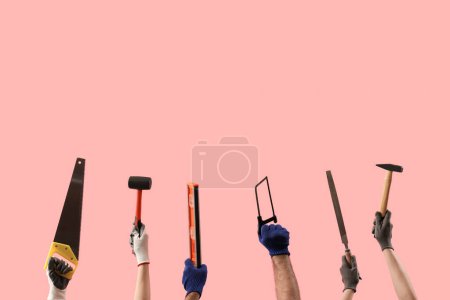 Téléchargez les photos : Mains féminines et masculines tenant différents outils de construction sur fond rose - en image libre de droit