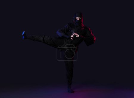 Téléchargez les photos : Ninja masculin avec shurikens sur fond noir - en image libre de droit