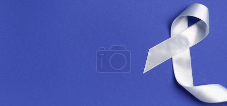 Photo for Silver awareness ribbon on blue background with space for text. Parkinson's Disease concept - Royalty Free Image