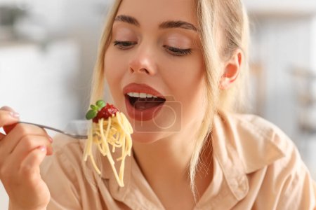 Foto de Mujer joven comiendo pasta sabrosa en la cocina, primer plano - Imagen libre de derechos