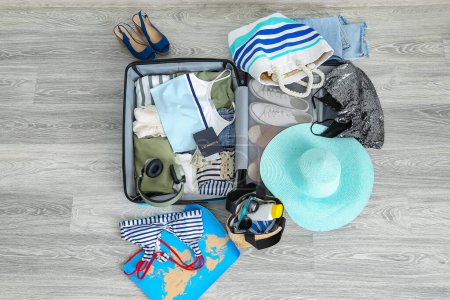 Foto de Maleta con ropa, accesorios de playa, pasaporte y entradas en el piso. Concepto de viaje - Imagen libre de derechos