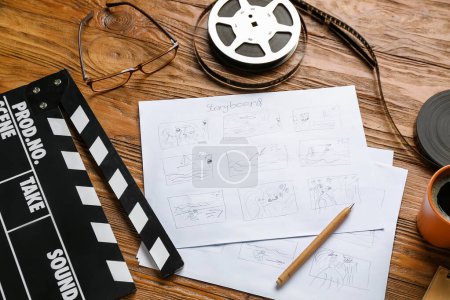 Téléchargez les photos : Storyboard avec film clapper et bobine de film sur fond en bois - en image libre de droit