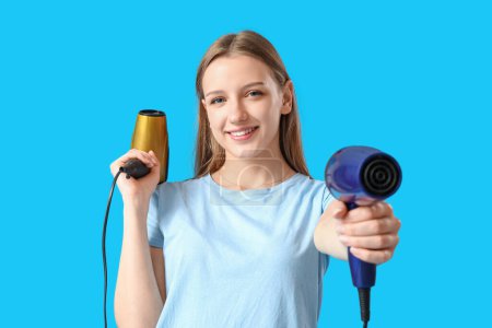 Photo for Beautiful young woman with hair dryers on light blue background - Royalty Free Image