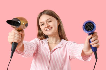 Photo for Beautiful young woman with hair dryers on pink background - Royalty Free Image