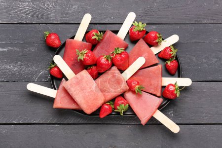 Photo for Tray with sweet strawberry ice-cream popsicles on black wooden background - Royalty Free Image