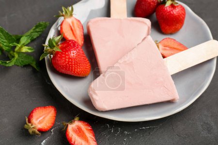 Photo for Plate with sweet strawberry ice-cream popsicles on black background - Royalty Free Image
