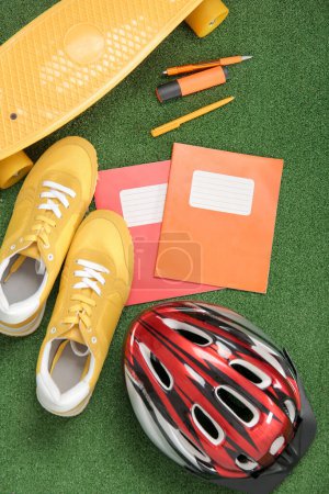 Foto de Casco de bicicleta con zapatillas, monopatín y diferentes artículos de papelería en el fondo de color - Imagen libre de derechos