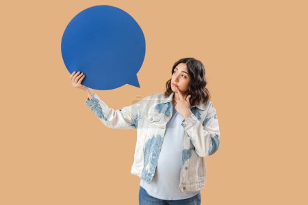 Thoughtful young pregnant woman with blank speech bubble on beige background