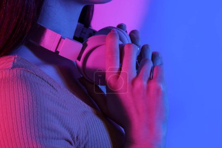 Junge Frau mit Kopfhörer hört Musik auf farbigem Hintergrund