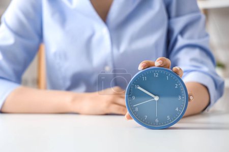 Photo for Businesswoman touching alarm clock on table, closeup. Time management concept - Royalty Free Image
