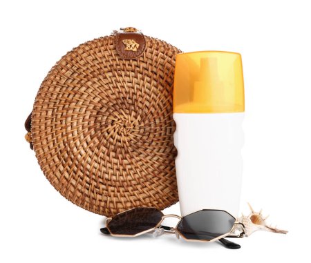Bolsa de mimbre con gafas de sol, botellas de crema protector solar y concha aislada sobre fondo blanco