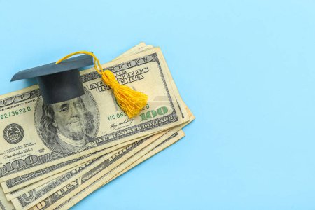 Foto de Composición creativa con billetes en dólares y tope de graduación sobre fondo azul - Imagen libre de derechos