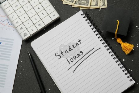 Notizblock mit Text STUDENT LOANS, Taschenrechner, Dollarnoten und Graduiertenmütze auf schwarzem Hintergrund