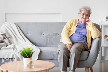 mujer mayor sentada en el sofá en casa