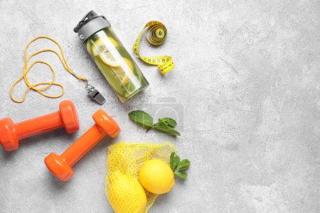 Téléchargez les photos : Bouteille de limonade sportive avec concombre et haltères sur fond blanc - en image libre de droit
