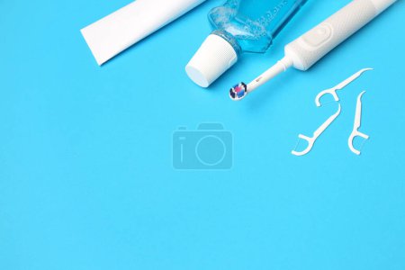 Foto de Escarbadientes, cepillo eléctrico, pasta y enjuague sobre fondo azul - Imagen libre de derechos