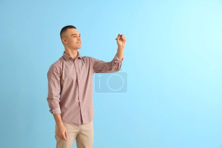 Male student with pen on blue background