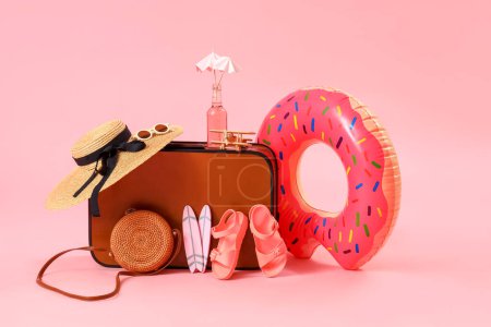 Foto de Maleta con anillo inflable y accesorios de playa sobre fondo rosa. Concepto de viaje - Imagen libre de derechos