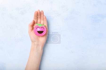 Téléchargez les photos : Main féminine tenant la balle de stress avec le visage heureux dessiné sur fond clair - en image libre de droit