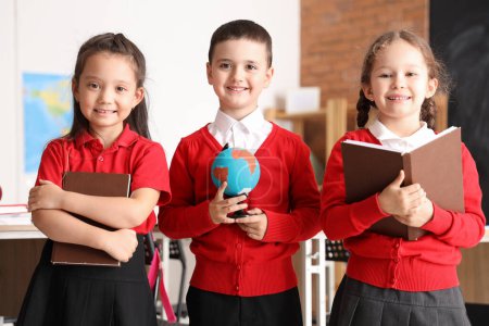 Photo for Little schoolchildren with globe and books in classroom - Royalty Free Image