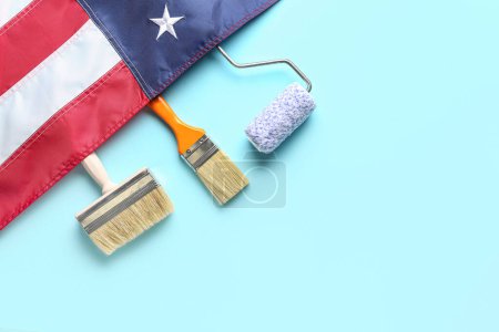 Téléchargez les photos : Rouleau de peinture, pinceaux et drapeau des États-Unis sur fond bleu. Fête du travail - en image libre de droit