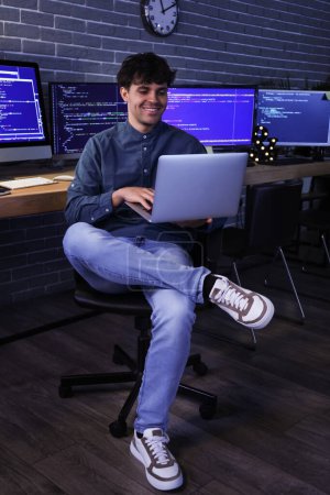 Photo for Male programmer working with laptop in office at night - Royalty Free Image