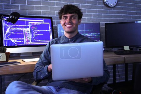 Téléchargez les photos : Programmeur masculin travaillant avec un ordinateur portable au bureau la nuit - en image libre de droit