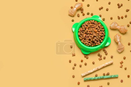 Composición con comida seca para perros y golosinas sobre fondo de color