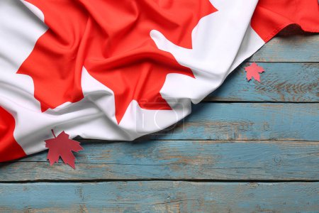 Foto de Bandera de Canadá y hojas de arce sobre fondo de madera azul - Imagen libre de derechos