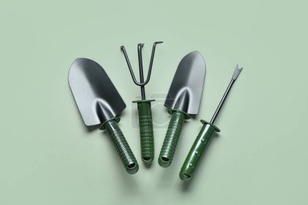 Photo for Gardening rake, shovels and weeder on green background - Royalty Free Image