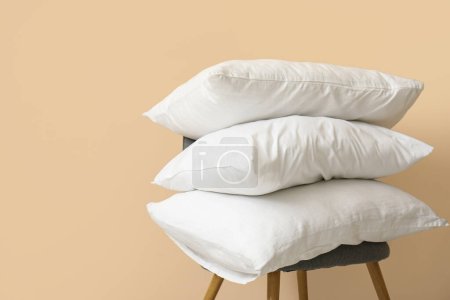 Almohadas blancas en silla cerca de la pared beige