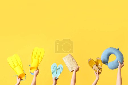 Foto de Muchas manos sosteniendo diferentes accesorios de playa sobre fondo amarillo - Imagen libre de derechos