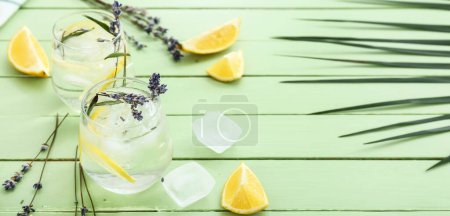 Glasses with cold lavender lemonade on green wooden background