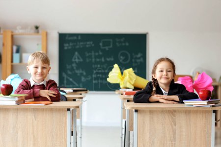 Glückliche Klassenkameraden mit Schultüten sitzen im Klassenzimmer am Schreibtisch