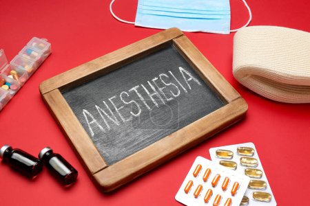 Foto de Pizarra con palabra ANESTESIA y suministros médicos sobre fondo rojo - Imagen libre de derechos