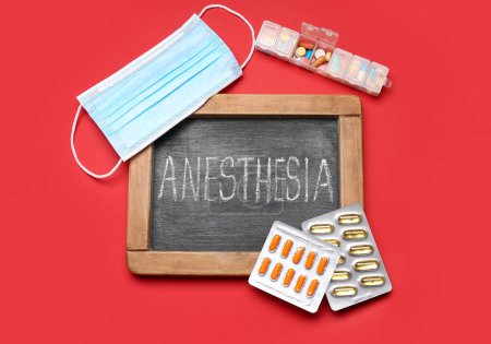 Foto de Pizarra con palabra ANESTESIA, pastillas y máscara médica sobre fondo rojo - Imagen libre de derechos