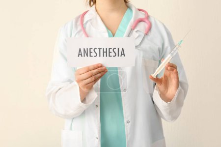 Photo for Female doctor holding paper with word ANESTHESIA on beige background, closeup - Royalty Free Image