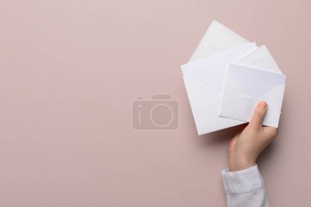 Female hand with envelopes and blank cards on color background