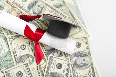 Foto de Tapa de graduación, diploma y billetes en dólares sobre fondo gris. Concepto de préstamo estudiantil - Imagen libre de derechos
