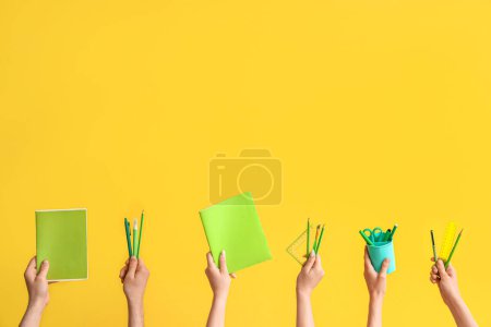 Téléchargez les photos : Hands with school supplies on yellow background - en image libre de droit