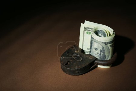 Foto de Billetes de dólar con candado sobre fondo marrón oscuro. Concepto de sanciones - Imagen libre de derechos