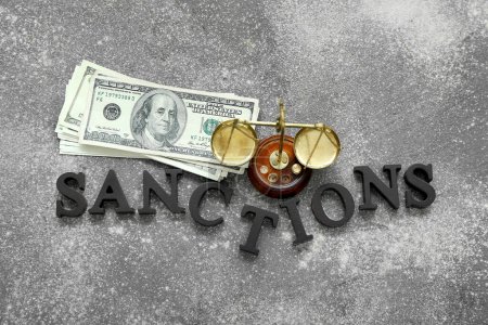 Foto de SANCIONES Word con escalas de justicia y billetes de dólar sobre fondo oscuro - Imagen libre de derechos